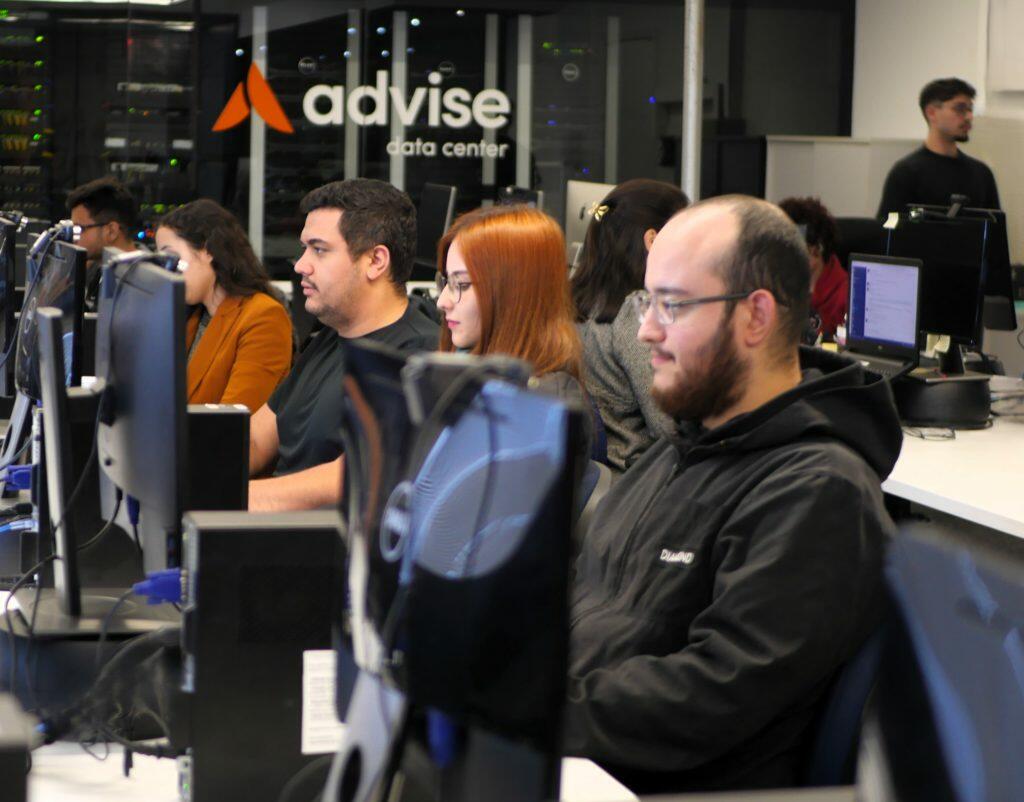 A imagem mostra funcionários da Advise trabalhando na sede da empresa em Londrina,.